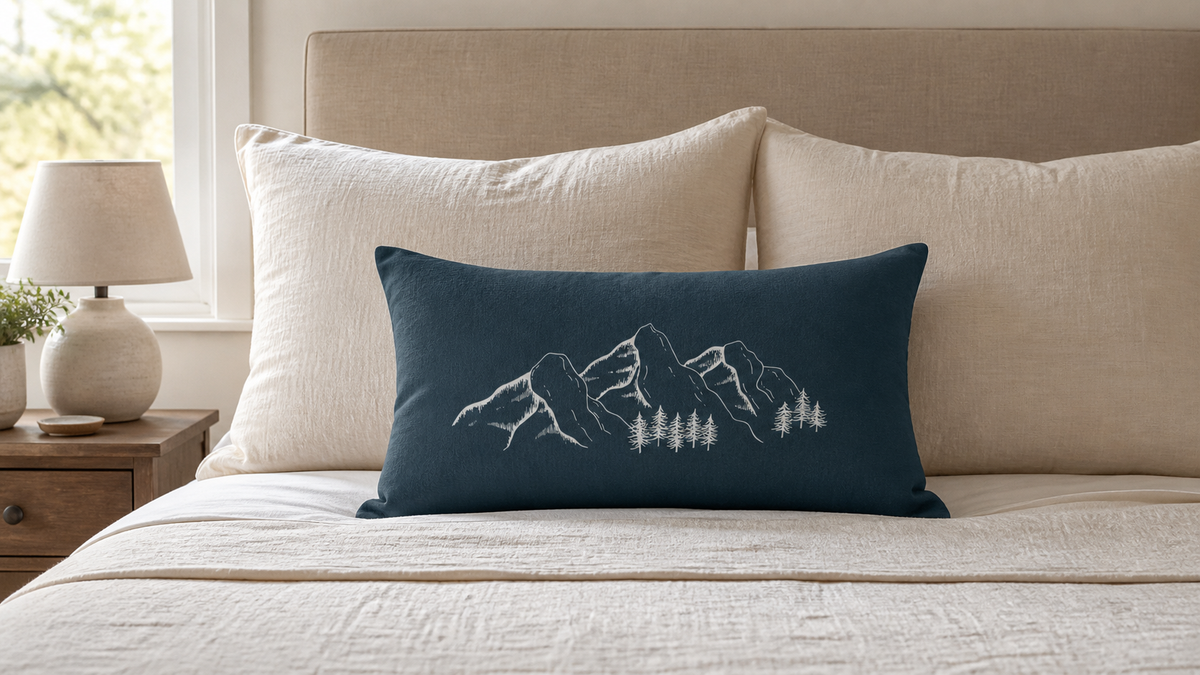 Green mountain lumbar pillow on a cream bed.